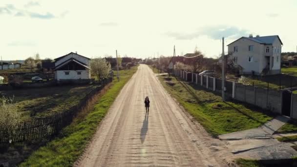 작은 집 과꽃이 피는 정원을 따라 넓은 시골 길을 따라 기쁘게 달리고 있는 한 소녀의 모습 — 비디오
