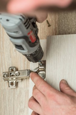 Dolap kapısı menteşesi ayarlanıyor.