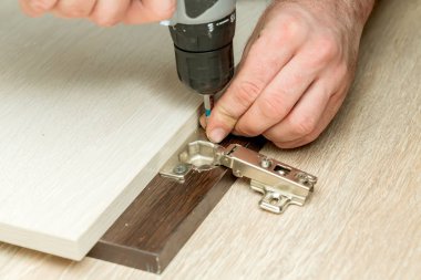 Dolap kapısı menteşesi ayarlanıyor.