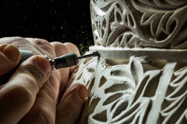 Kirli eller sıva yüzeyine süs oyuyor.