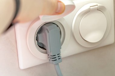 Kadın eli, elektrik prizinin koruyucu kapağını kaldırır.