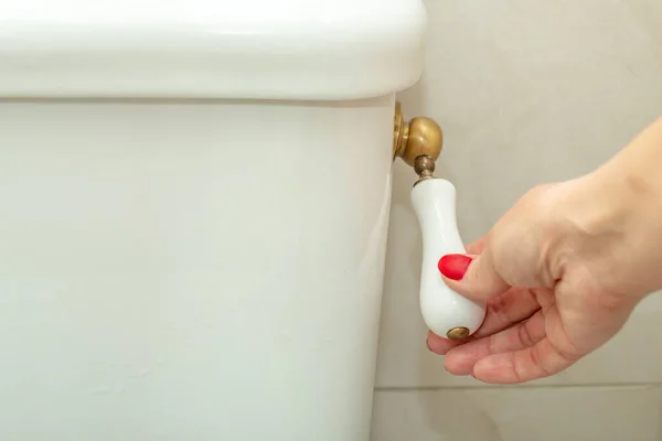 Femme main vers le bas de la poignée de toilette — Photo