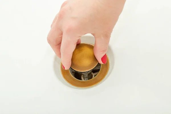 Female hand holds bathtub drain plug — Stock Photo, Image