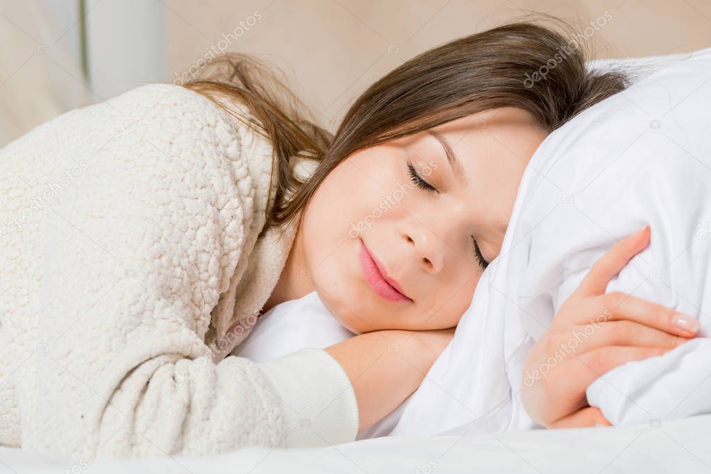 Portrait of a young woman sleeping on the bed at home