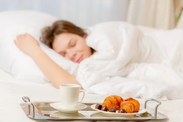 Jeune femme endormie et plateau avec son petit déjeuner dans la chambre — Photo