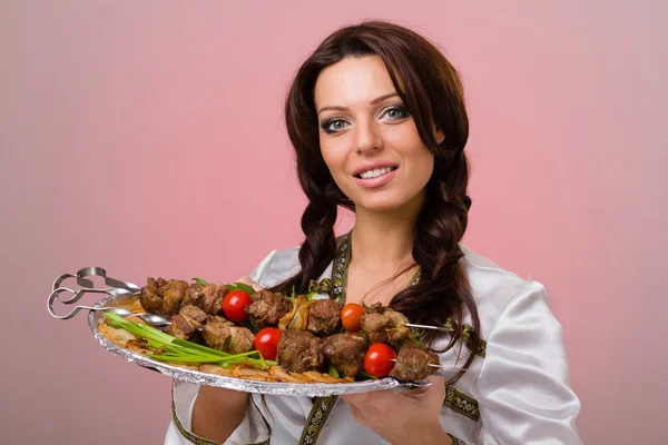 Camareros llevando platos con carne sobre fondo rosa — Foto de Stock