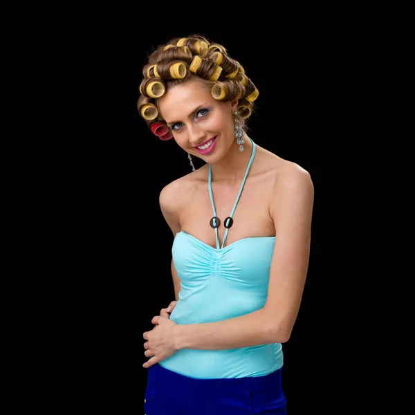 Beautiful coquette young woman with curlers, isolated on black — Stock Photo, Image