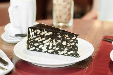 Kafede beyaz bir fincan tabağında çikolatalı pasta..