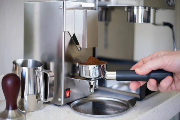 Grind coffee into the portafilter of the espresso machine, selective focus.