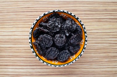 Ahşap bir masada, bir tabakta kurumuş kuru erik..