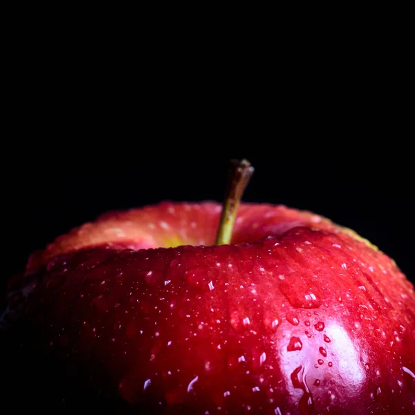 Red wet apple on a black background, close up.