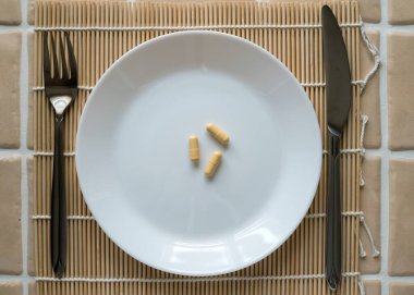 Öğle yemeği için tablet kapsülü beyaz tabakta, üst görünümde..