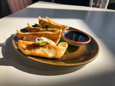 Kahverengi tabakta dört mükemmel hamur, beyaz bir masada soya sosu.