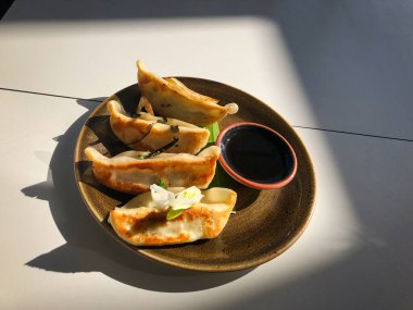 Kahverengi tabakta dört mükemmel hamur, beyaz bir masada soya sosu.