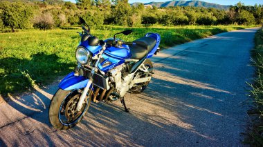 Yoldaki boş mavi motosiklet güzel mavi renkli ve aynalı, dairesel farlı klasik tarz.