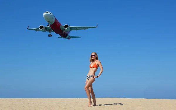 Woman have fun on the beach and landing plane. Traveling on an airplane concept. Text space. Island Phuket in Thailand. Impressive paradise. Hot beach Mai Khao. Amazing landscape