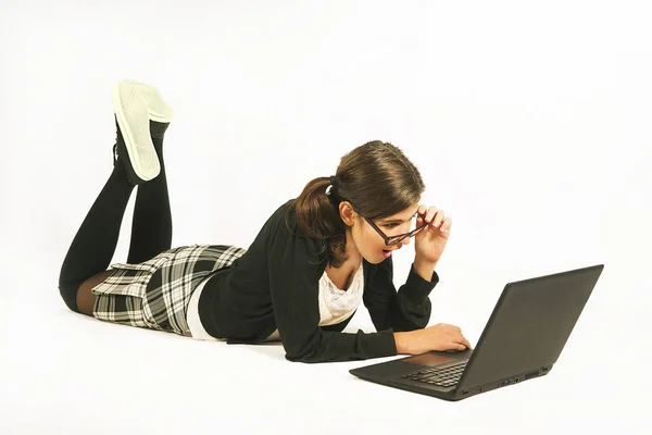 Flicka som ligger på golvet med en bärbar dator Stockbild