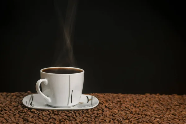 Горячий кофе в чашке, касающиеся кофейных зерен — стоковое фото