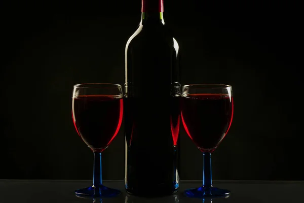 Copos e garrafa de vinho isolados sobre fundo preto — Fotografia de Stock