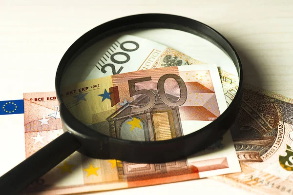 Billetes polacos y billetes en euros bajo la lupa . — Foto de Stock