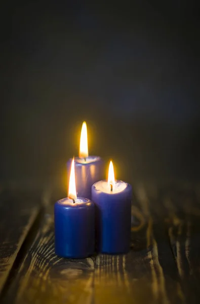 Encender tres velas azules en el mostrador de madera —  Fotos de Stock