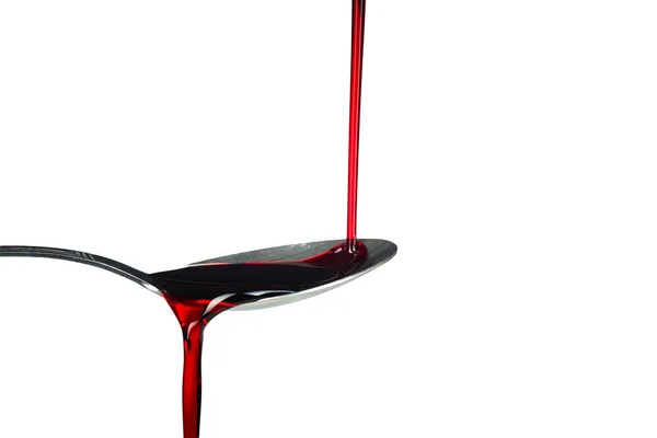 Red thick liquid brimming over on the spoon on the white background — Stock Photo, Image