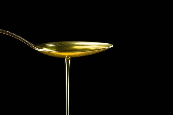 Spoonful of oil on the black background — Stock Photo, Image