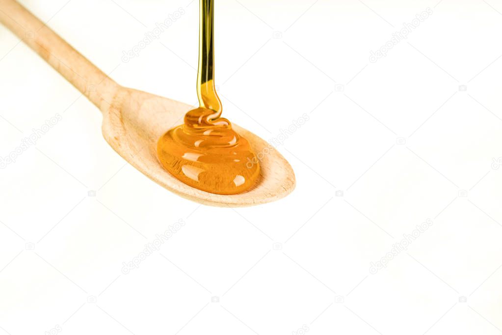 Spoonful of honey on the wooden spoon on the white background 