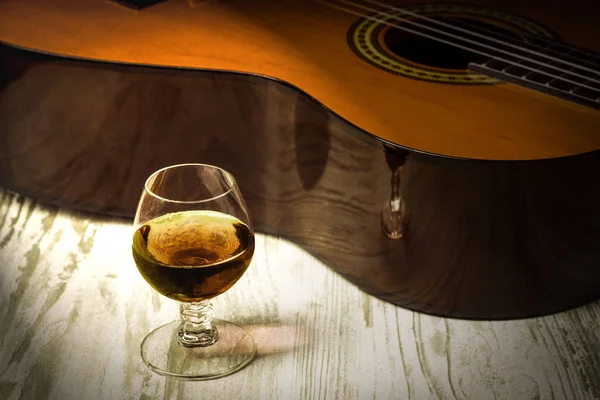 Concept achter de muziek de gitaar, de glas cognac — Stockfoto