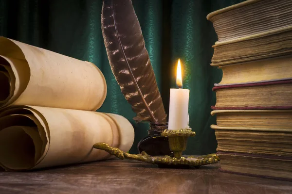 Zwoje pergaminu, stos książek i zapalona świeca. — Zdjęcie stockowe
