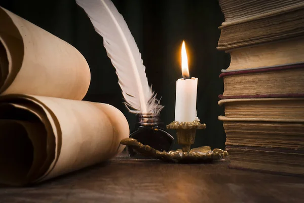 Rullar av pergament, en bunt böcker, och ett tänt ljus — Stockfoto