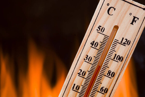 Концепция изменения климата, деревянный термометр на фоне пламени
