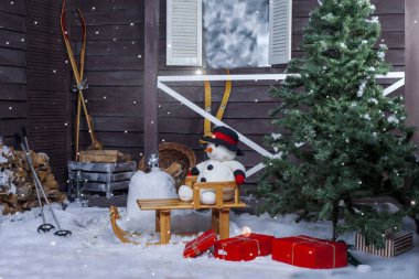 Bir Noel ağacı içinde belgili tanımlık geçmiş vasıl ev ile ahşap bir atlı kızak kardan adam. Noel.