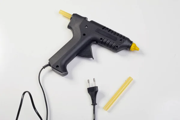 Таяние - клеевой пистолет со съемными клеевыми палочками на белом фоне — стоковое фото