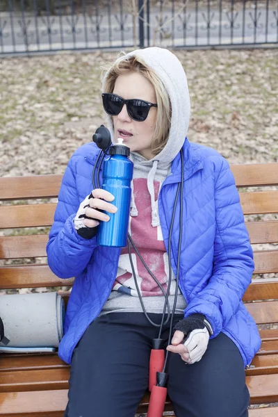 Una mujer después de entrenar bebe agua de una botella deportiva —  Fotos de Stock