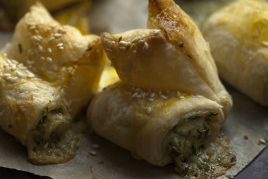 Pasta puf böreği peynir ve yeşillik ile üzerinden. Susam serpin.