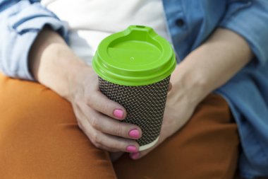 Kahve bir kadının elinde bir kağıt bardak. Bir bankta oturur. Yakın çekim