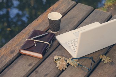 Boş dizüstü ekran bulanık doğanın bir arka plan üzerinde ahşap bir masa üzerinde. Grafik ekran veya ürün yüklemesi için.