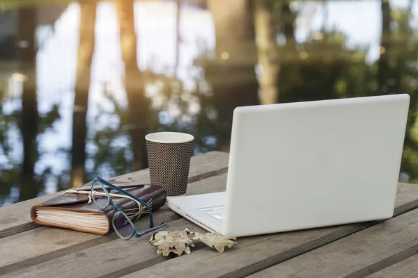 Boş dizüstü ekran bulanık doğanın bir arka plan üzerinde ahşap bir masa üzerinde. Grafik ekran veya ürün yüklemesi için.