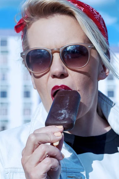 Beautiful blonde with red lips eating chocolate ice cream outdoors