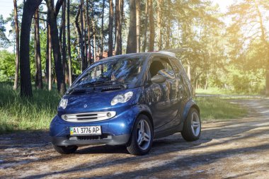 Kiev, Ukrayna - 17 Temmuz 2017: Smart City Coupe sabahın erken saatlerinde ormanda duruyor. Güneş ışınları