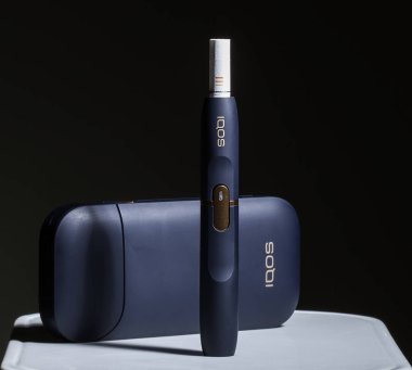 Kiev, Ukrayna - 16 Kasım 2019: En son elektronik sigaralar, Iqos tütün ısıtma sistemi, sigara içmek, siyah arka planda koyu mavi.