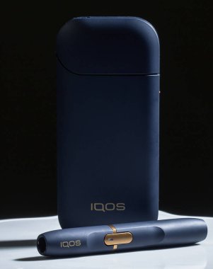 Kiev, Ukrayna - 16 Kasım 2019: En son elektronik sigaralar, Iqos tütün ısıtma sistemi, sigara içmek, siyah arka planda koyu mavi.