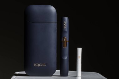 Kiev, Ukrayna - 16 Kasım 2019: En son elektronik sigaralar, Iqos tütün ısıtma sistemi, sigara içmek, siyah arka planda koyu mavi.