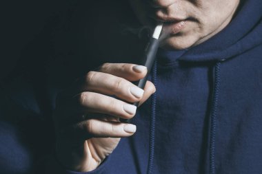 Kiev, Ukrayna - 16 Kasım 2019: Iqos tütün ısıtma sistemi eldeki kişinin arka planına karşı, Iqos tütün teknolojisi