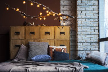 Noel, yeni yılın tavan arası geniş bir pencere, duvarların siyah arkaplan, çelenkler, lambalı Noel ağacı ve yeni yıl hediyeleri, ekoseli yatak.