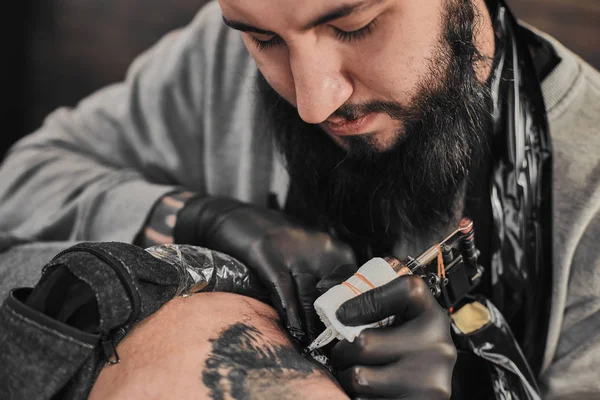 Mestre de tatuagem está tatuando no tatuador — Fotografia de Stock