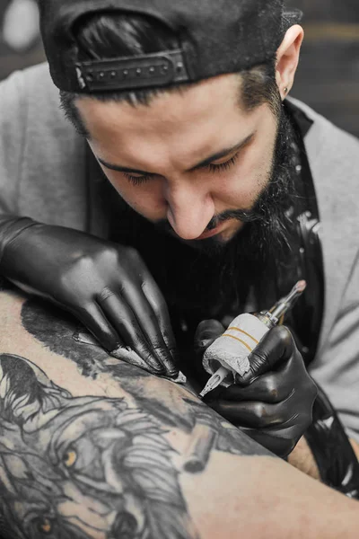Le maître du tatouage tatoue dans le salon de tatouage — Photo