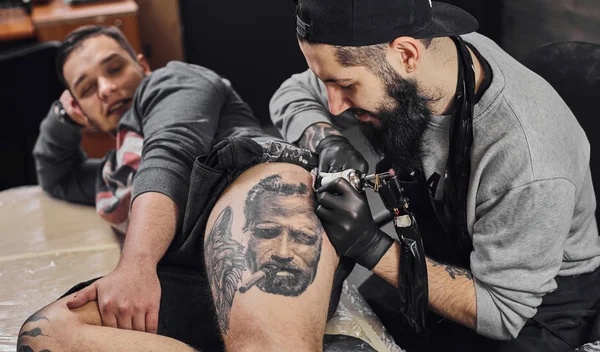 Le maître du tatouage tatoue dans le salon de tatouage — Photo