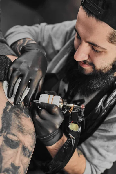 Tattoo master is tattooing in the tattoosalon